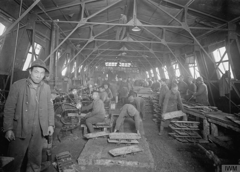 Black and white picture inside a warehouse. It is filled with Chinese workers.